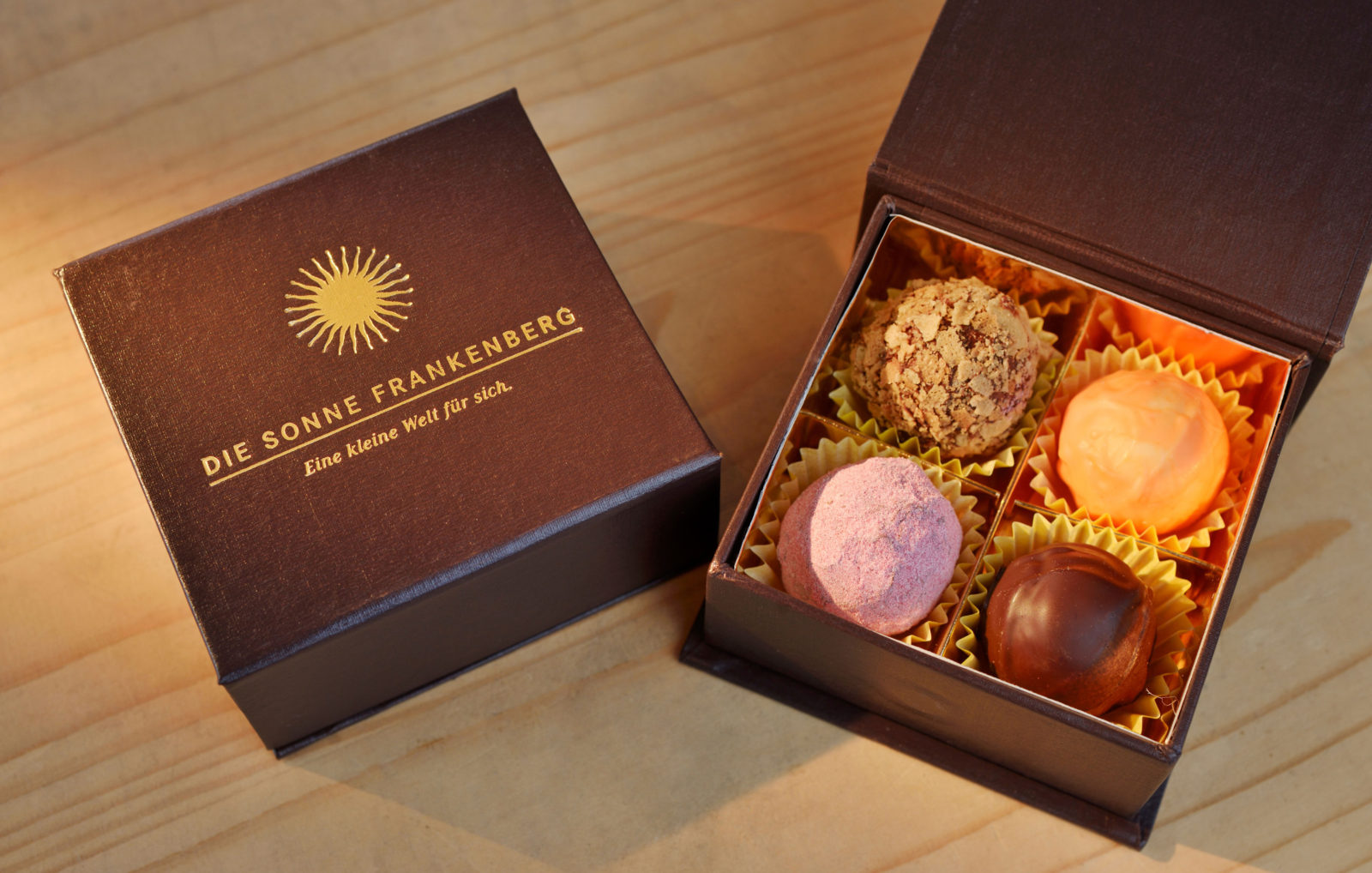 4 Pralinen in einer Schachtel auf einem Untergrund aus Holz