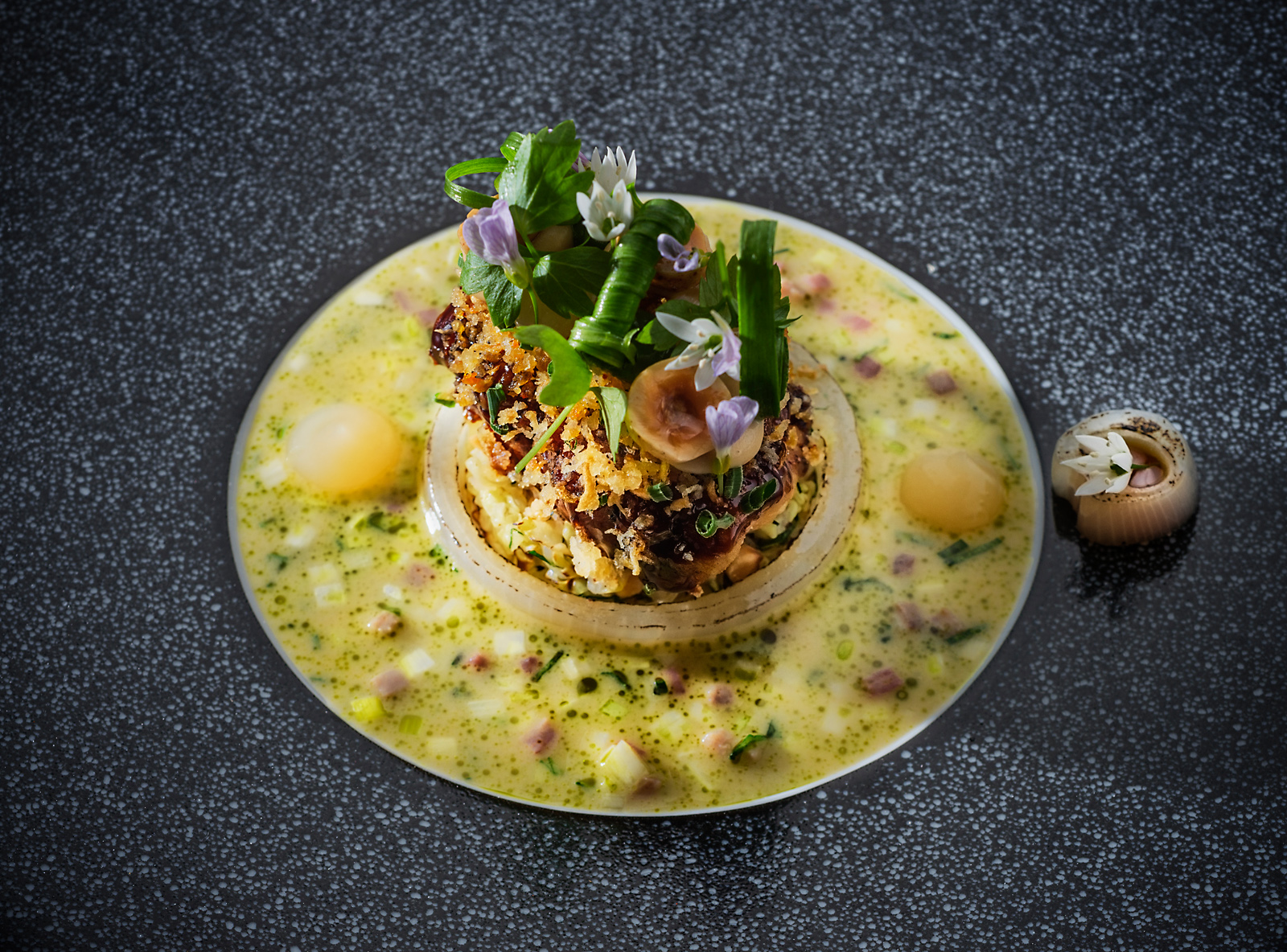 Suppe auf schwarzem Porzellan, mit sommerlichen Blüten.